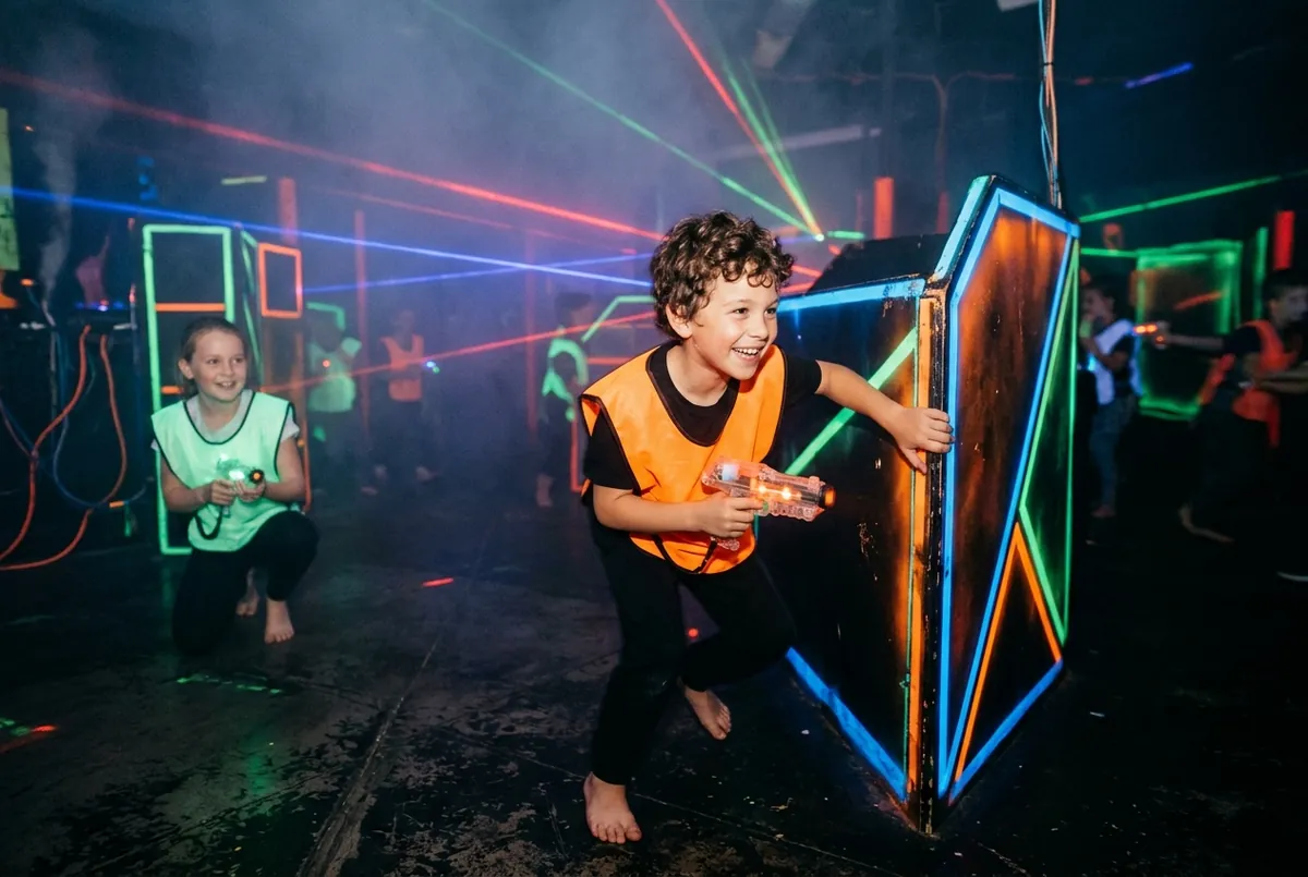 Enfants équipés de gilets lumineux dans une arène de laser game